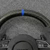 Close-up of bright blue 12 o'clock center mark and glossy carbon fiber texture on Audi S6 steering wheel