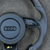 Close view JIONX S3 performance badge on flat bottom forged carbon steering wheel spoke