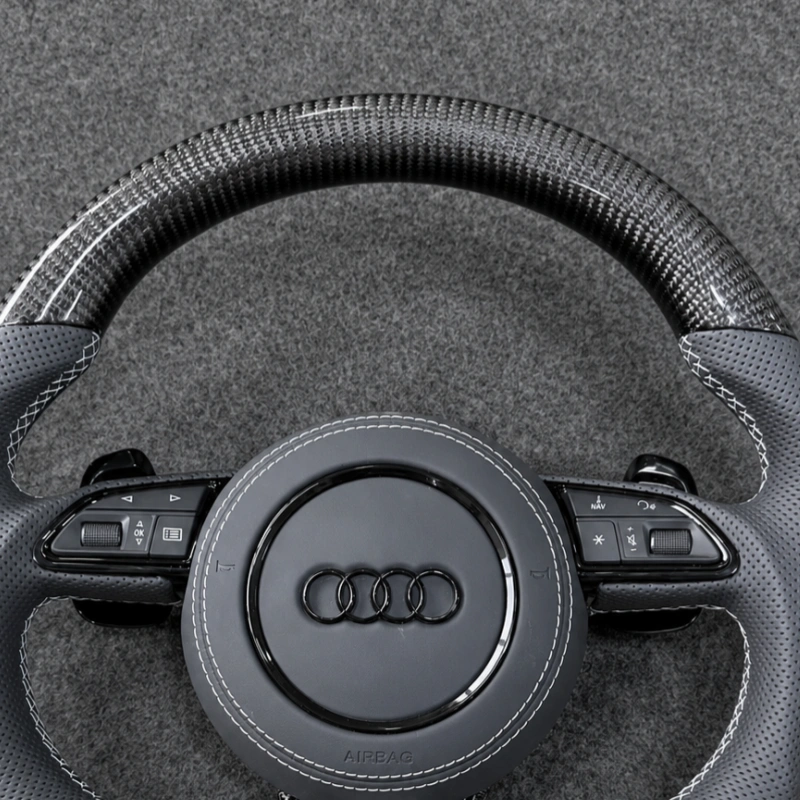 Closeup glossy carbon fiber rim for Audi steering wheel, clear woven racing texture