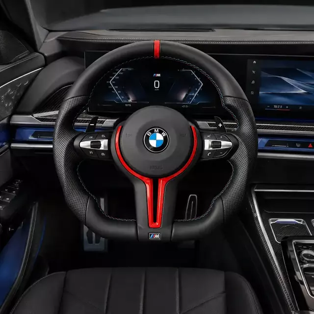 Custom red-trim steering wheel installed in a BMW 7 Series M-style cockpit with perforated grips and paddle shifters
