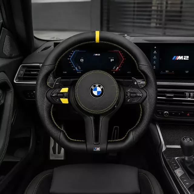 BMW M2 interior with installed steering wheel featuring a black Nappa leather airbag cover and yellow accents