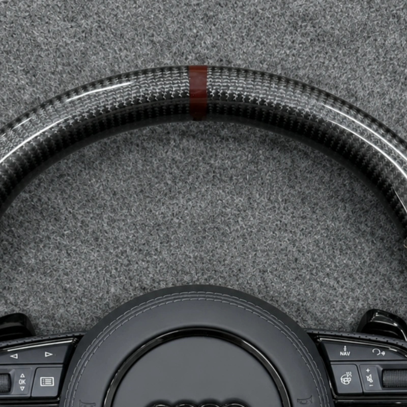 Close-up of dark brown center marker and glossy carbon fiber texture on Audi RS sport steering wheel