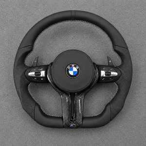 Custom all-black Nappa leather steering wheel for BMW M4 with perforated grips, white stitching and real carbon fiber trim