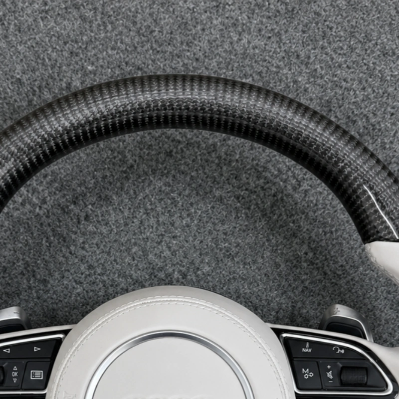 Close up glossy carbon fiber rim of two tone flat bottom white leather steering wheel for Audi A3 Q5 RS7