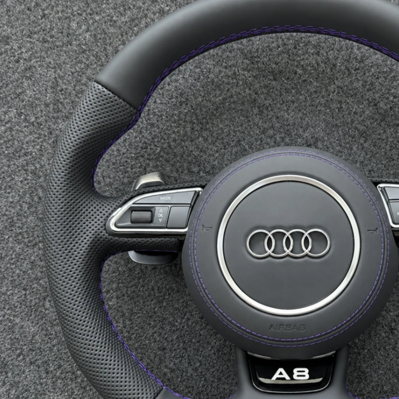 Close up of perforated black Nappa leather grips and purple contrast stitching on Audi flat bottom steering wheel