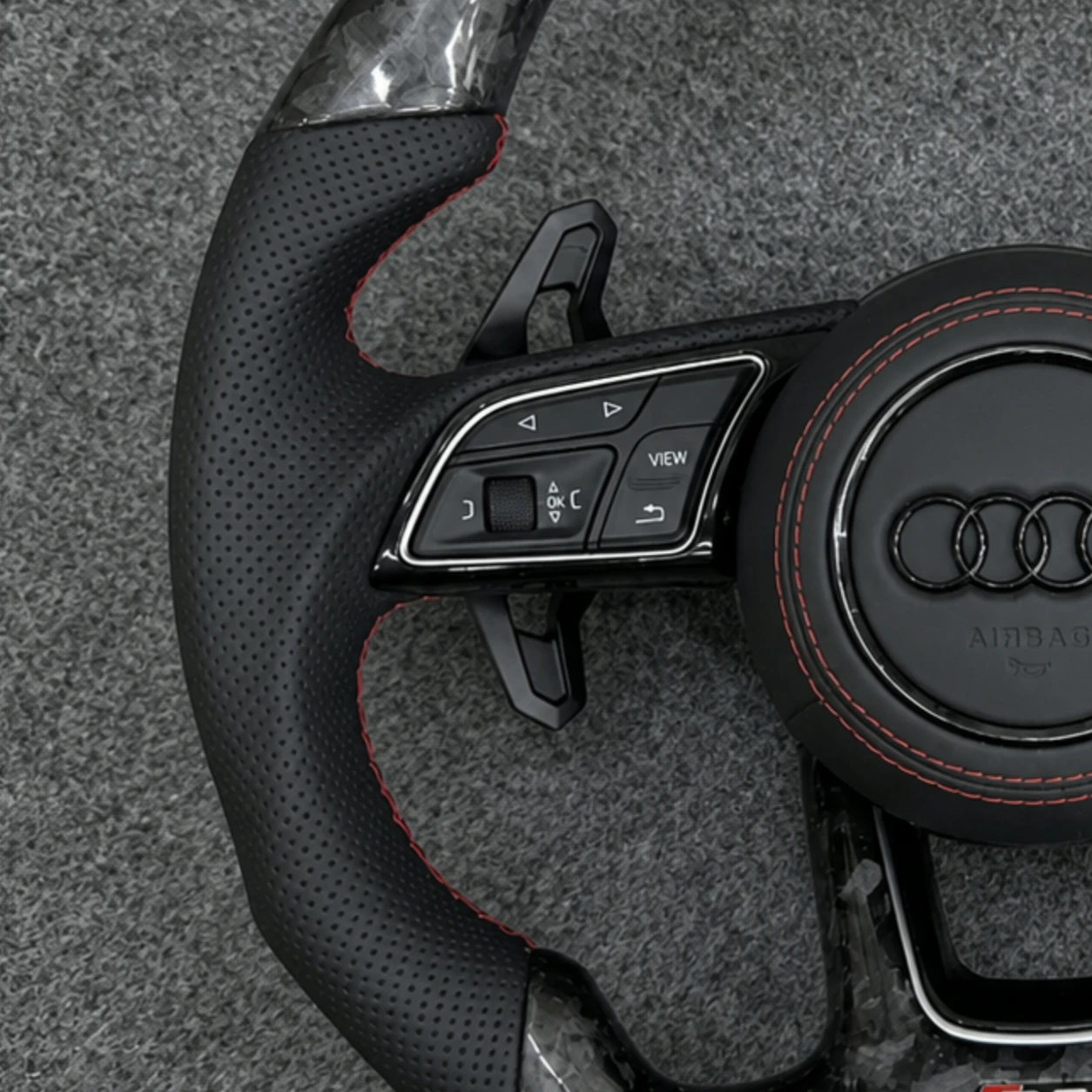 Perforated leather grips with red contrast stitching Audi steering wheel closeup