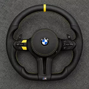 BMW M sport steering wheel with black Nappa leather airbag cover, yellow stitching and accents on gray carpet
