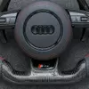 JIONX S Line metal badge closeup on gloss carbon fiber steering wheel