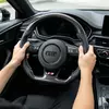 Installed interior view of Audi carbon flat steering wheel, perforated leather, white stitching, S sport badge
